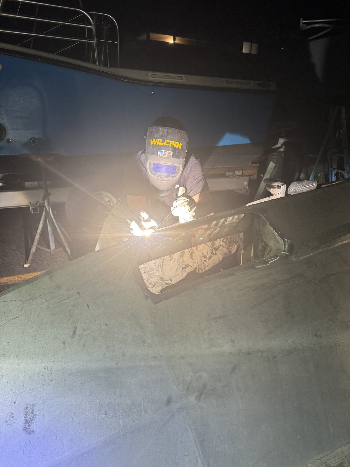 Welder TIG welding a new plate section into an aluminum hull